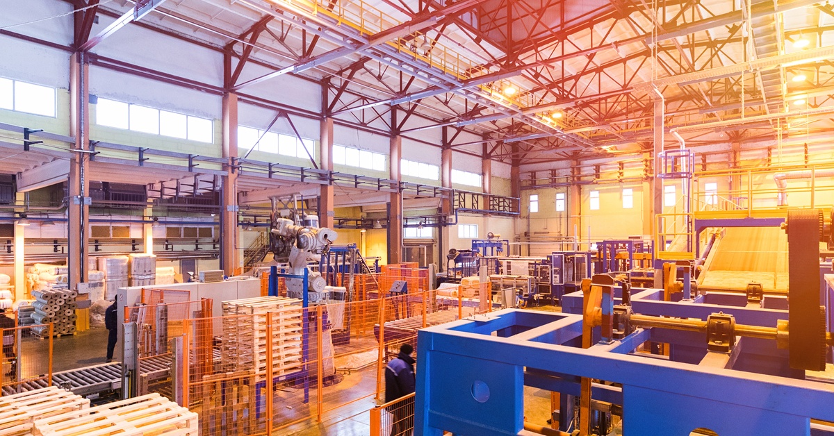 An expansive warehouse shows machines and automation systems in place, with wooden pallets used throughout the setup.