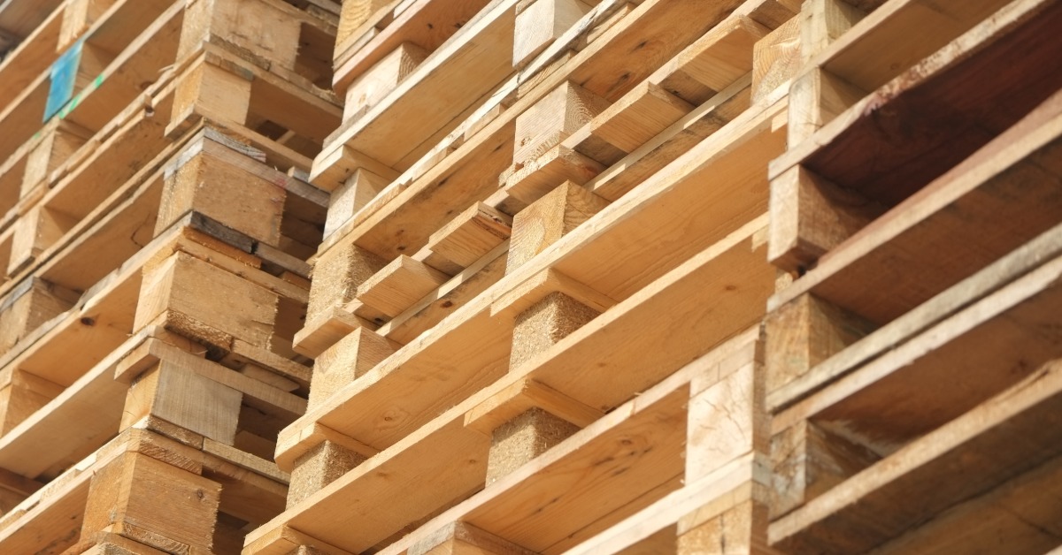 Stacks of wooden shipping pallets are arranged in a storage area, showing materials used for warehousing operations.